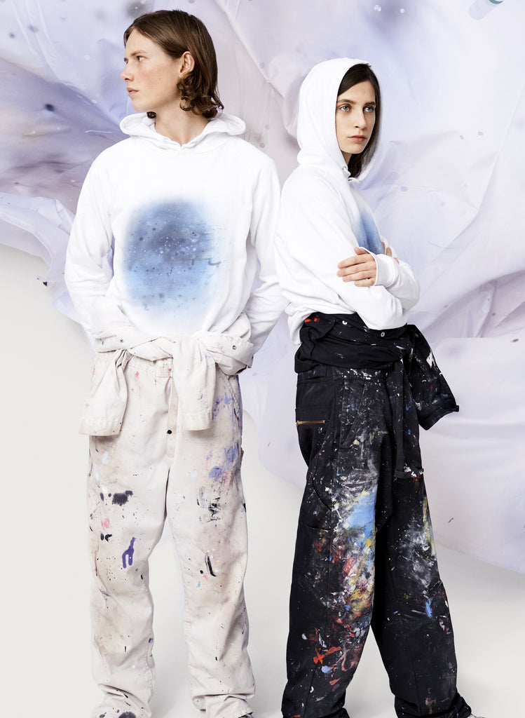 Female and male models wearing white sweatshirts with blue, artistic design. Wearable art, unisex hoodie for him and her. 