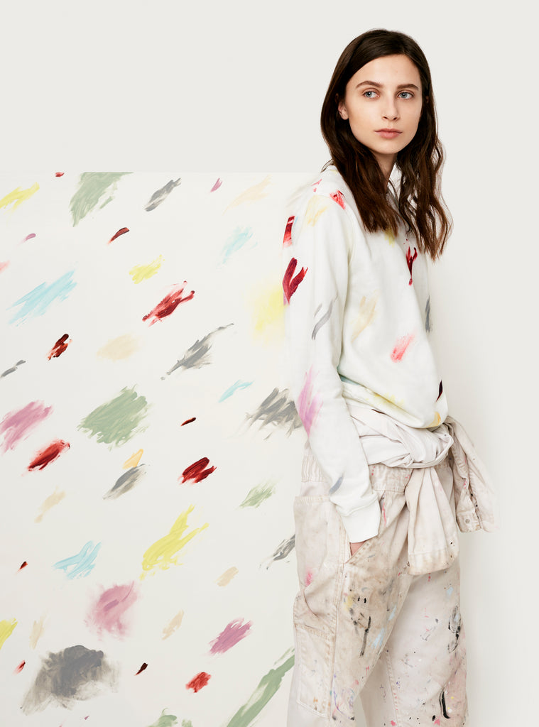 Female model wearing white sweatshirt with colourful artistic design. Wearable art hoodie made from organic cotton material. Artistic version front.