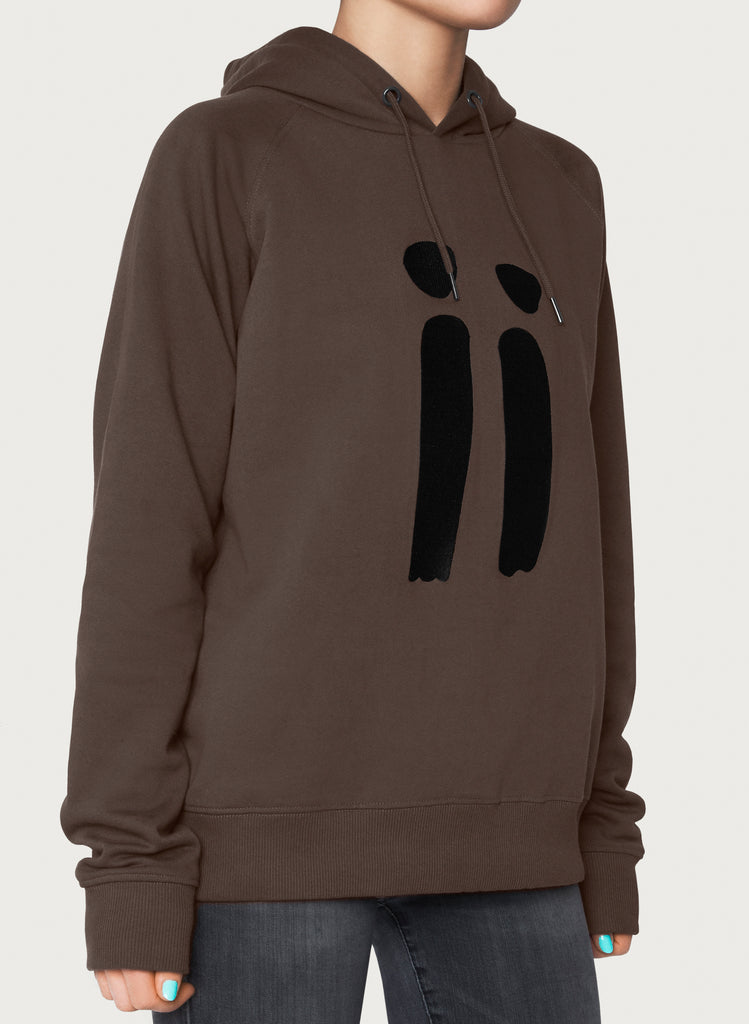 Female model presenting brown, unisex sweatshirt with ARTiiG logo on. Wearable art hoodie for him and her. Front picture.