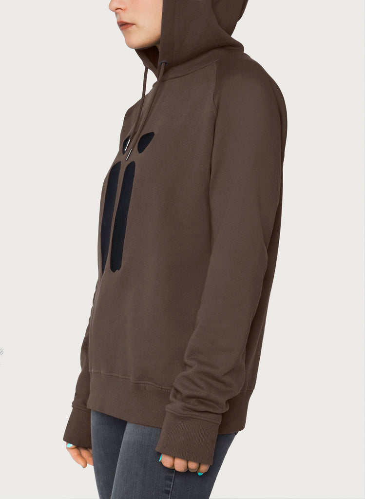 Female model presenting brown, unisex sweatshirt with ARTiiG logo on. Wearable art hoodie for him and her. Side view.