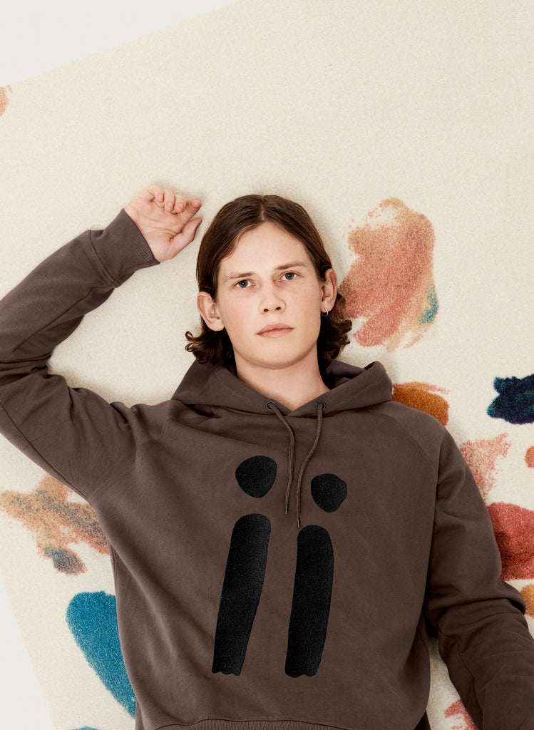 Male model presenting brown, unisex sweatshirt with ARTiiG logo on. Wearable art hoodie for him and her. Artistic version.